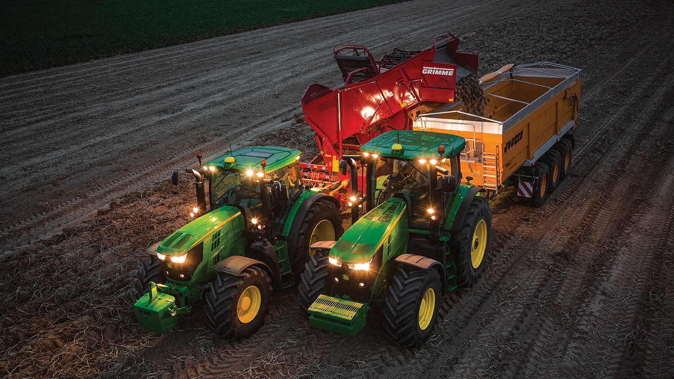 Kartulikoristusmasinat vedav traktor laadib kartuleid maha kärusse, mida veab teine traktor