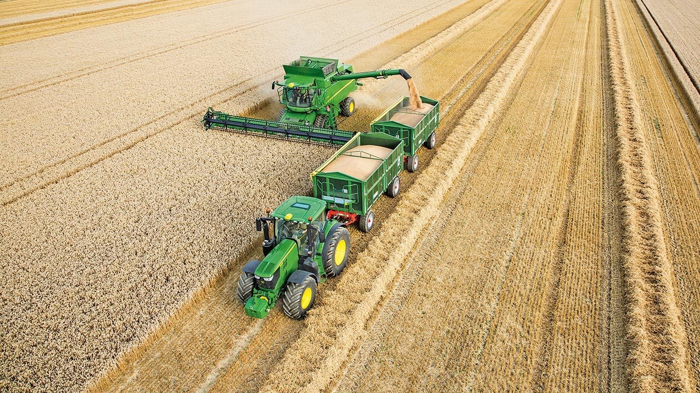 John Deere S-seeria kombain laadib nisu maha topelthaagisele, mida veab traktor