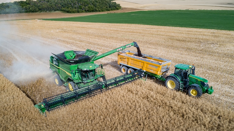 John Deere X-seeria kombain laadib rapsiseemet viljakärusse, mida veab John Deere'i traktor