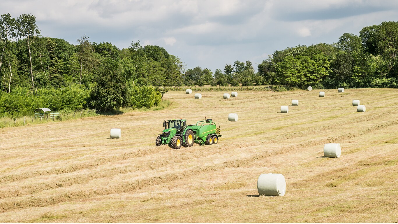 Rullipressiga John Deere’i traktor koos silopallidega põllul