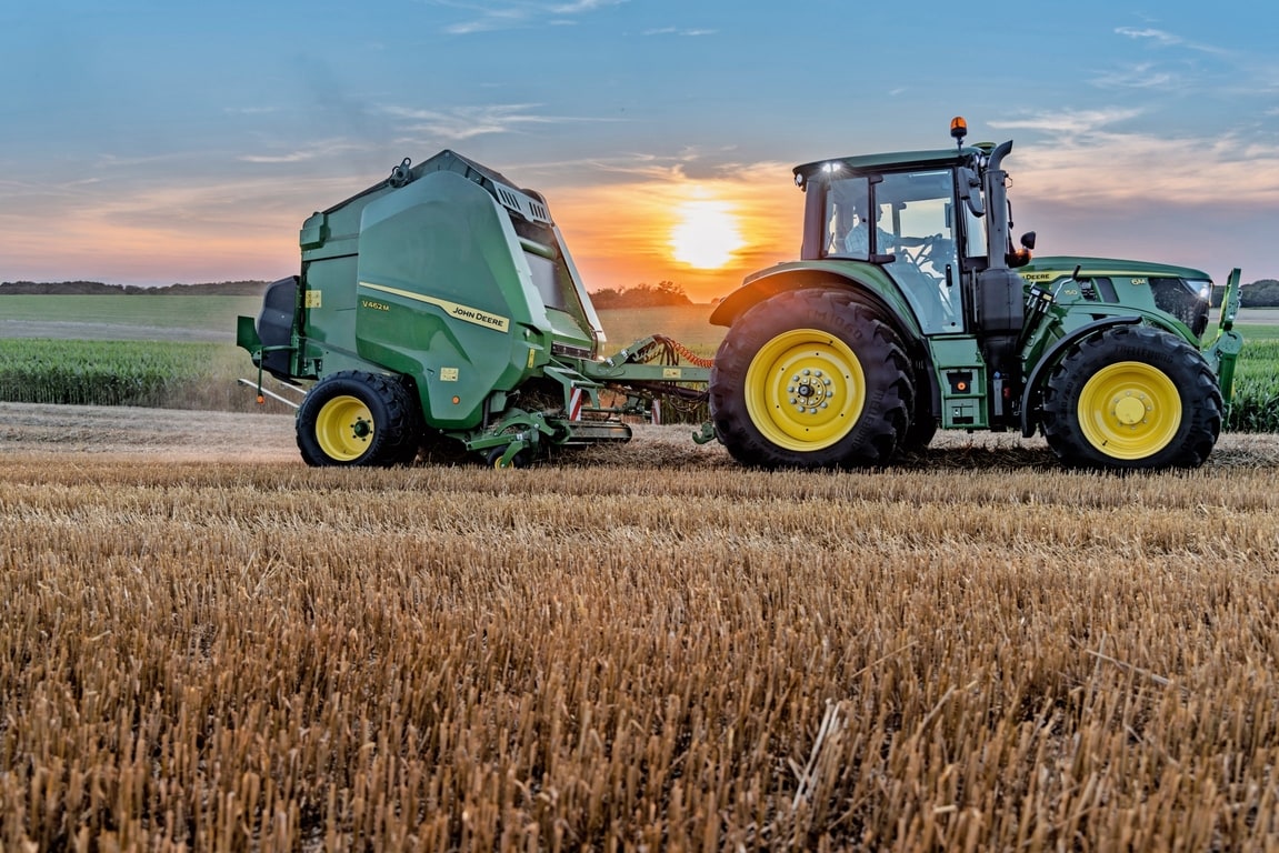John Deere V462M põhuväljal, mida tõmbab päikeseloojangul John Deere 6M 150