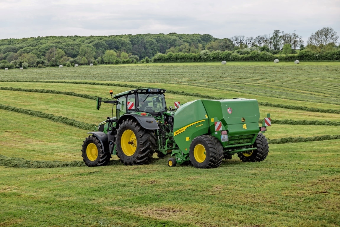 John Deere'i F442R rullipress, mida veab künklikul muruväljakul John Deere'i 6M traktor